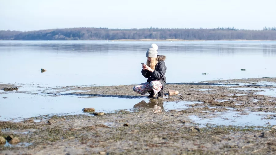 Pige fotograferer noget ved Roskilde Fjord. Foto af Martin Kunzendorf