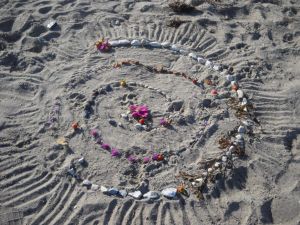 Mandala af blomster og sten fra stranden
