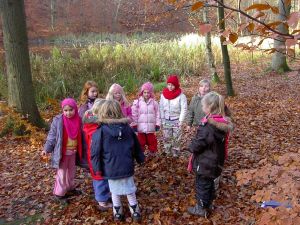 Eleverne kan digte sange om det de har lært. Her udeskolepiger fra Bybækskolen. Foto: Stinne Krarup Nielsen. Skolepiger står i en rundkreds i en skov