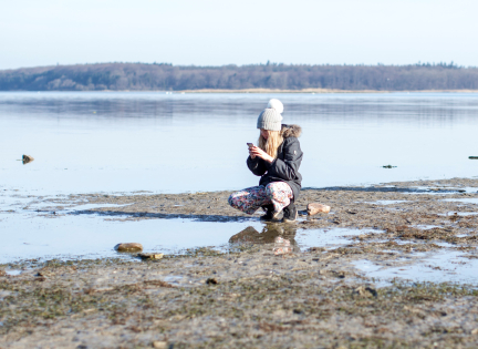 Pige fotograferer noget ved Roskilde Fjord. Foto af Martin Kunzendorf
